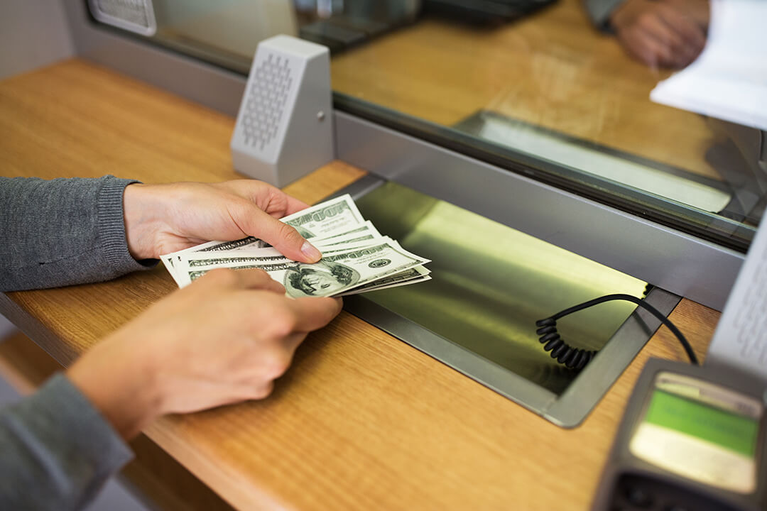 Lady depositing money to a bank teller.